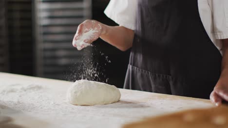 animation of hand of asian female baker preparing sourdough for bread