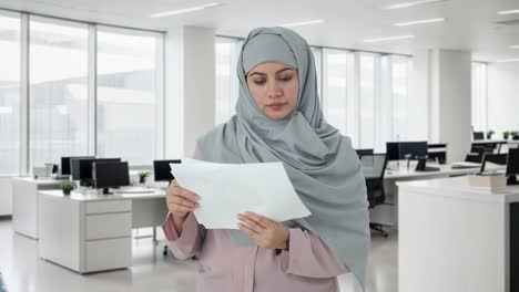 mujer de negocios musulmana leyendo informes en la oficina