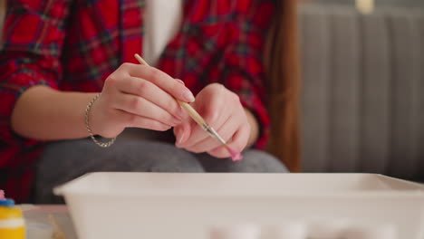 artist shakes off drops of pink paint into water in workshop