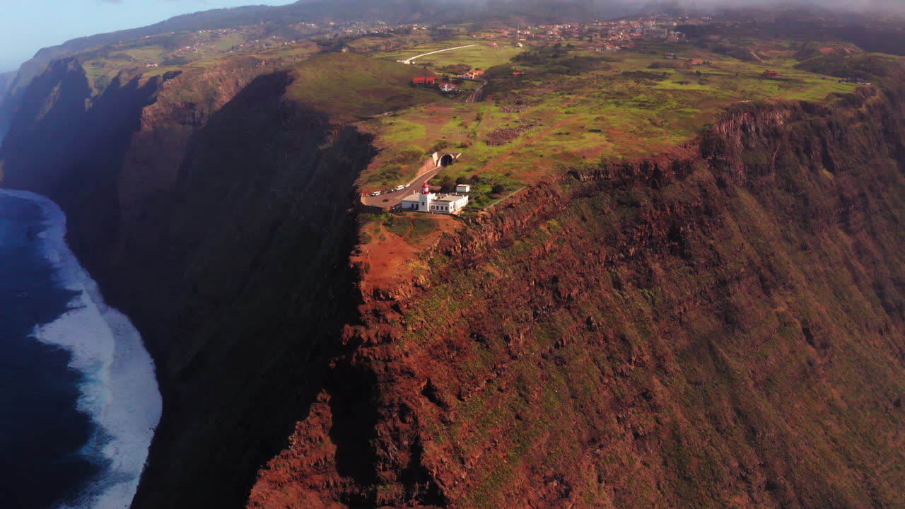 햇빛 아래 깊은 바다와 등대가 있는 거대한 절벽을 향한 공중 비행