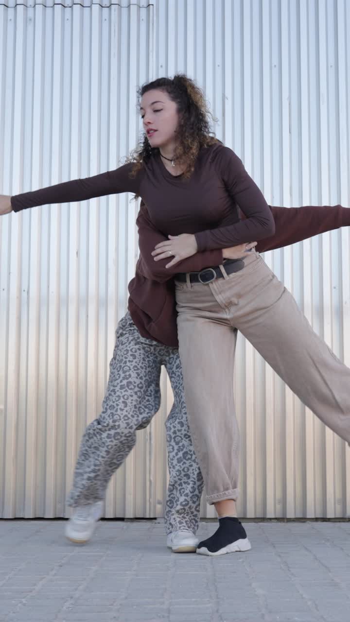 Two young women dancing a choreography in urban environment