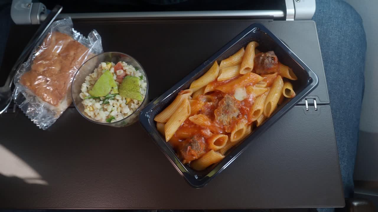bandeja de comida de avión con pasta y ensalada