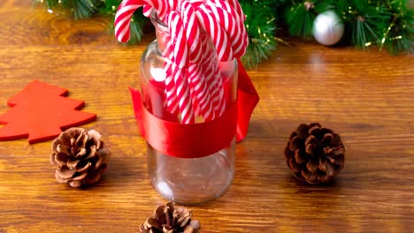 Animation-of-christmas-decorations,-candies,-jar,-pine-cones-on-wooden-background