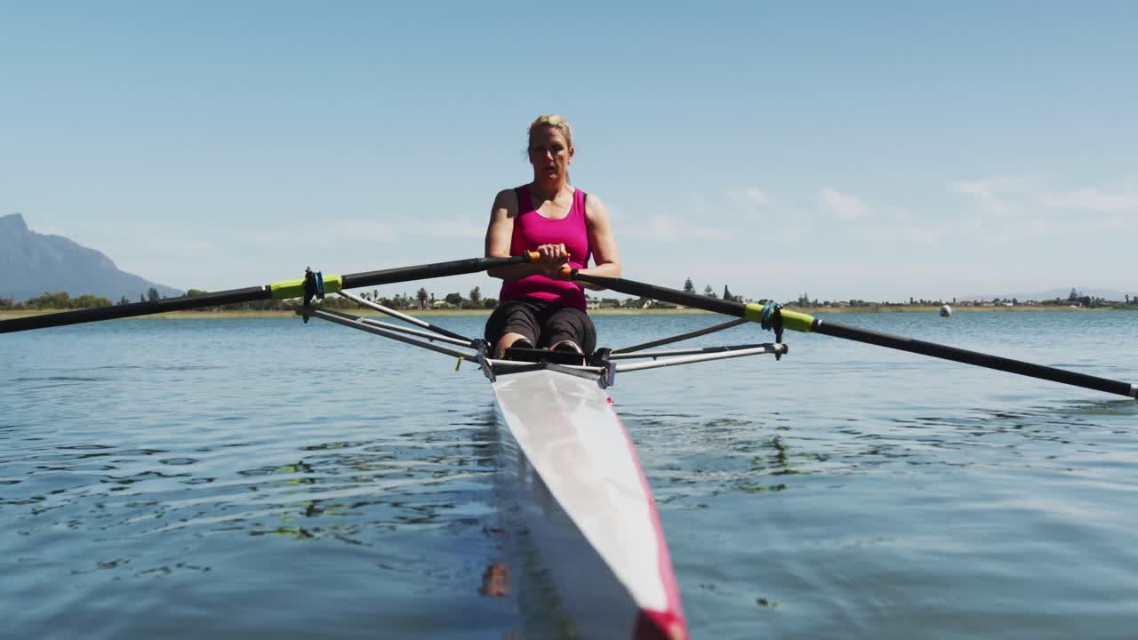 mujer caucásica mayor remando un barco en un río