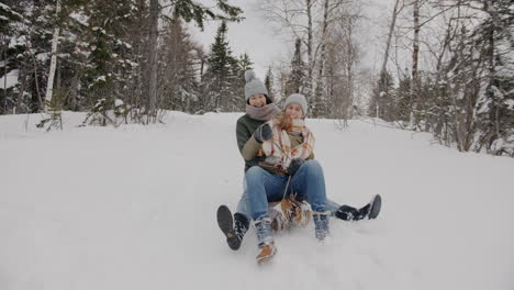 two women sledding in snowy forest