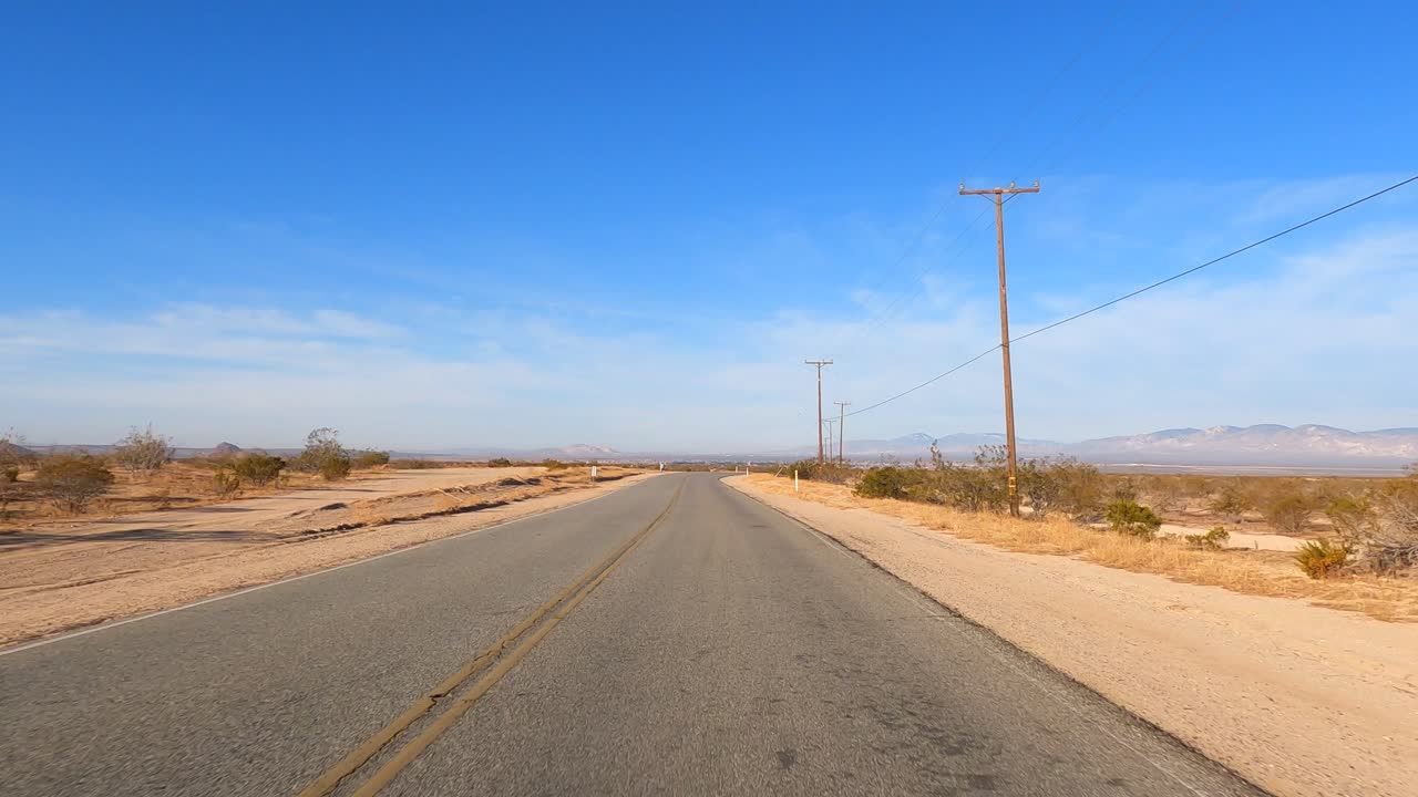 conduciendo por una carretera vacía a través del paisaje arenoso del desierto de mojave - punto de vista del conductor