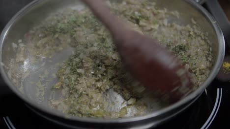 primer plano de un chef mezclando ingredientes en una sartén de metal