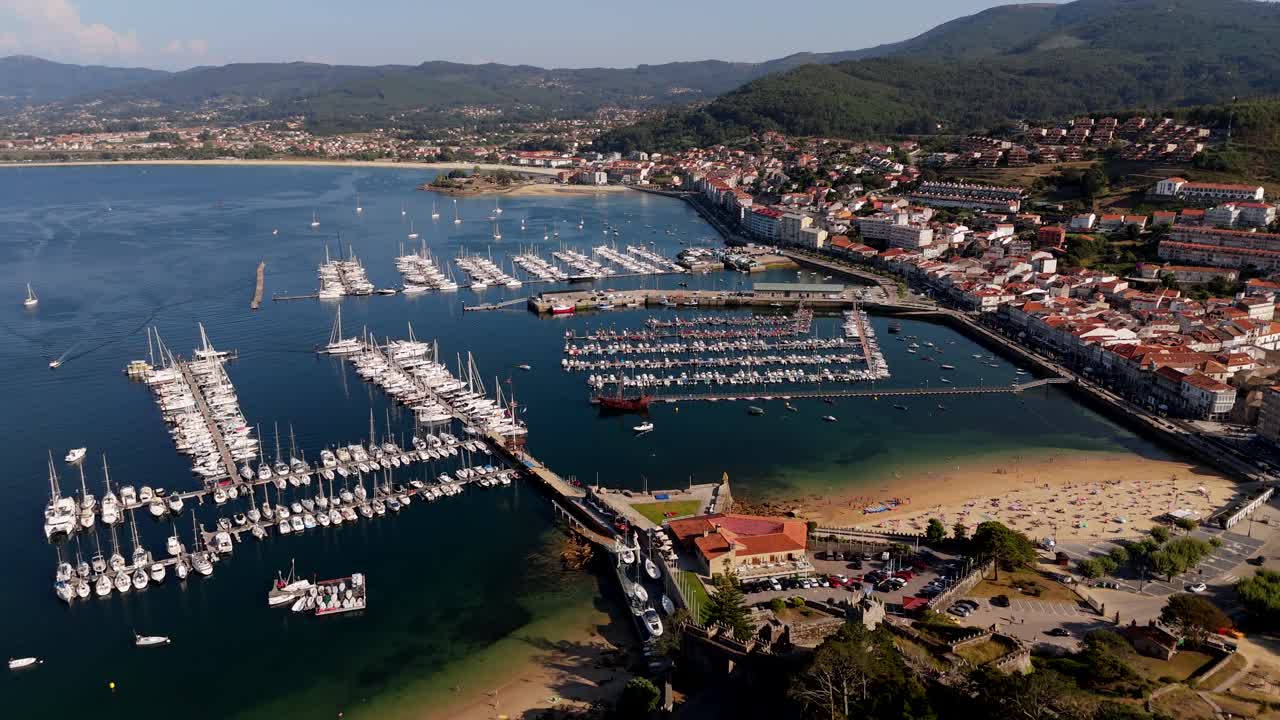 Vista aerea del porto turistico e del castello di Baiona, con barche ormeggiate e il villaggio sullo sfondo
