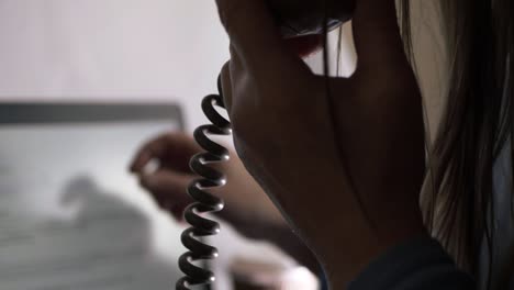 woman talking on the phone in office while pointing at laptop screen