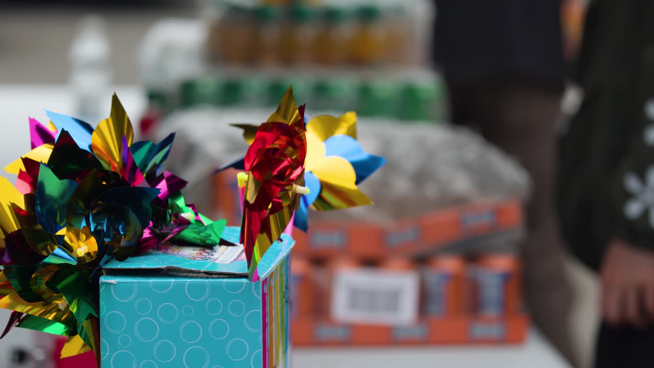 Bright metallic pinwheels spin in breeze on display at outdoor festival market, shallow focus