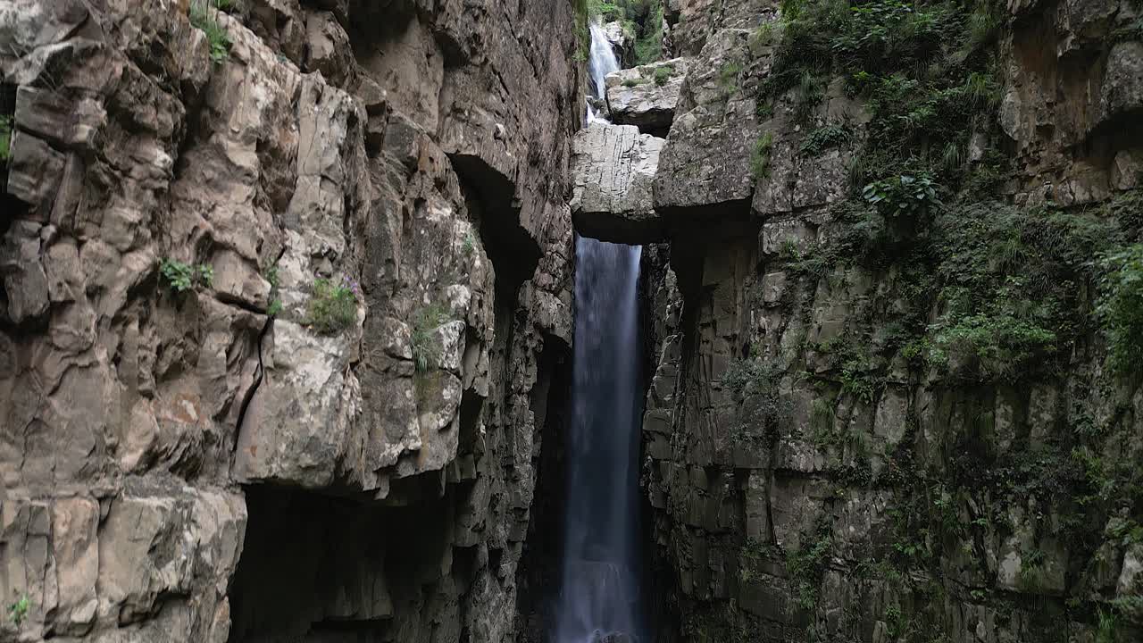 aérea asciende en un cañón de roca estrecho y oscuro con una gran cascada, la naturaleza