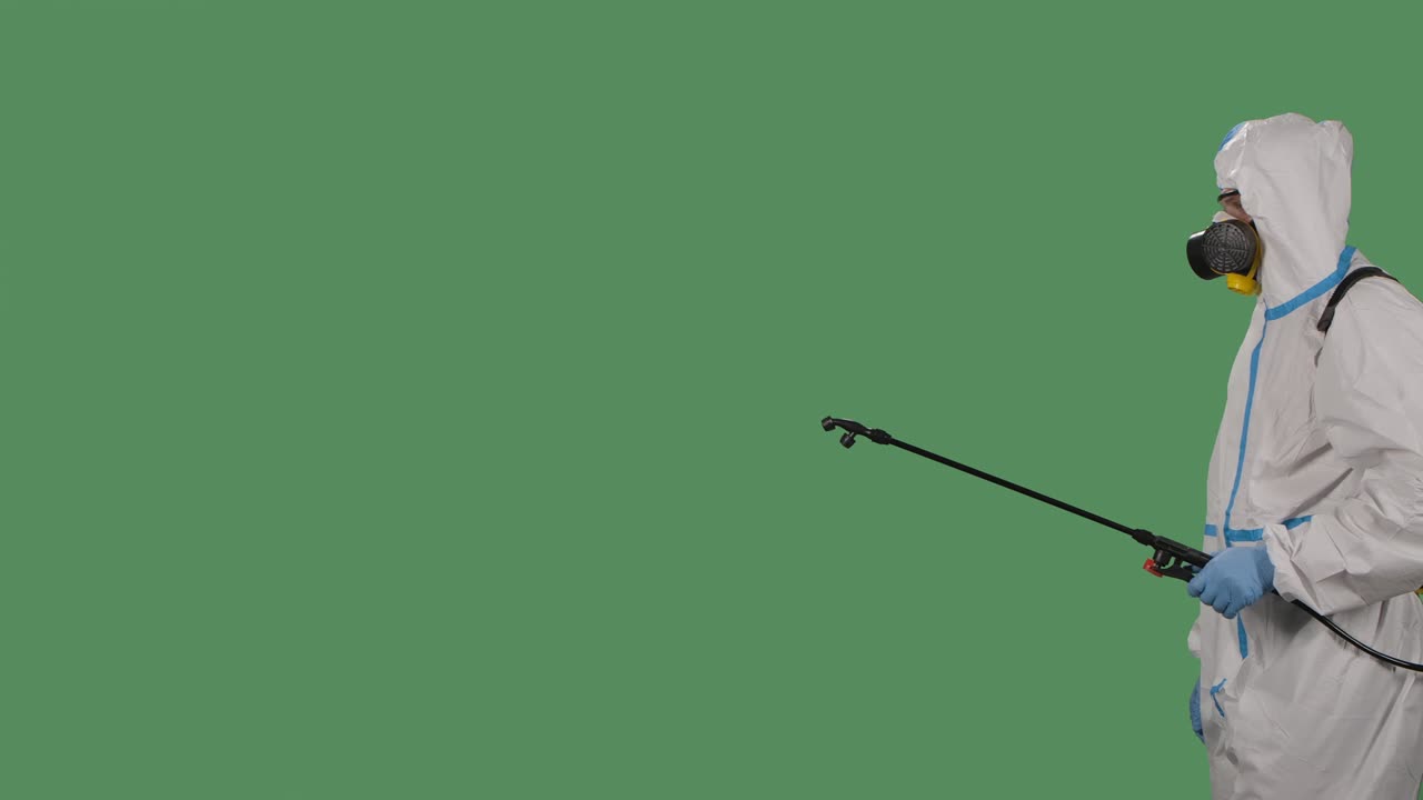 trabajador de desinfección con un traje blanco protector, respirador y gafas hace la desinfección en una pantalla verde, clave de croma. cerca. movimiento lento