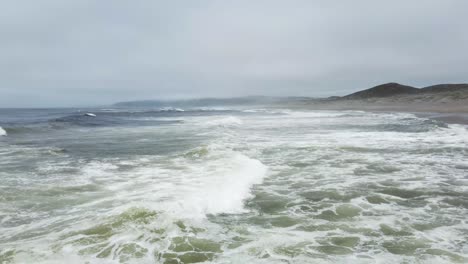 pullback shot of waves splashing in blue wide ocean, cool breeze, california