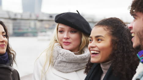 friends walking along south bank on winter visit to london