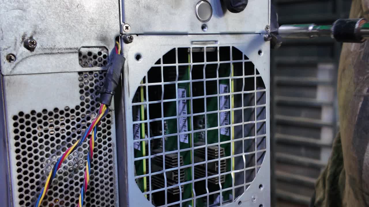 Handheld close-up of a technician servicing high-stakes Bitcoin mining hardware, emphasizing the intricate and dirty nature of the work