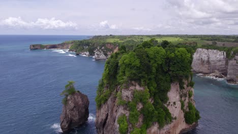 drone flies around lush green rock at sumba island during day time, aerial