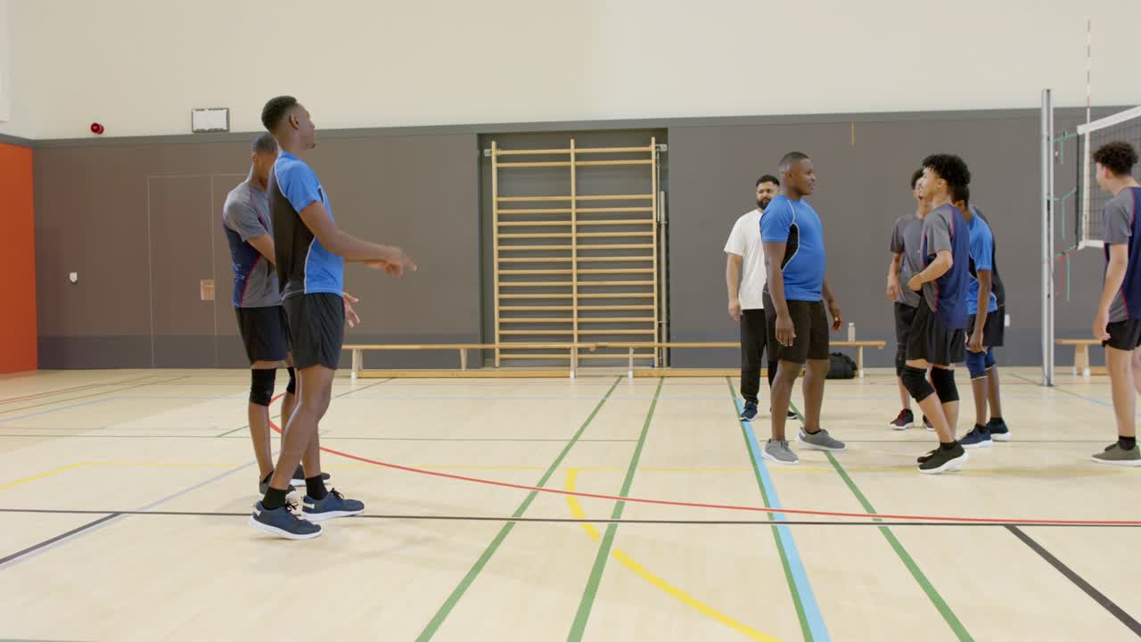 Treinador sinalizando jogador afro-americano lançando e sacando em rede de ginásio para treino, com espaço para texto
