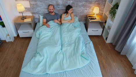 Top-view-of-young-couple-under-the-bed-sheets-in-the-morning