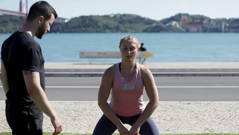 una atleta rubia deportiva entrenando con kettlebell al aire libre.