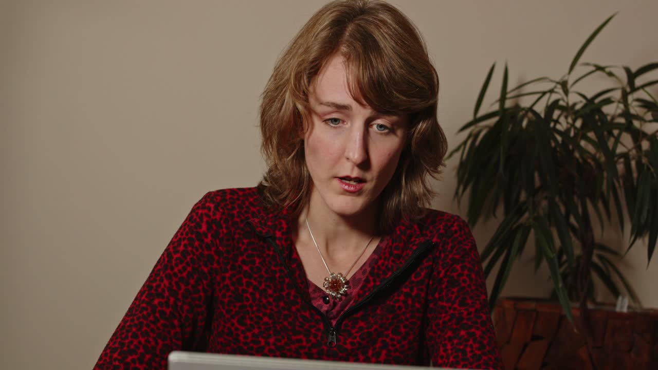 Zoom out of young woman in her 30's having a serious video call for work