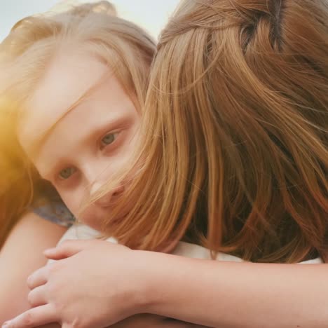 Mom-Hugs-Her-Daughter-At-Sunset-While-Wind-Plays-With-Their-Hair