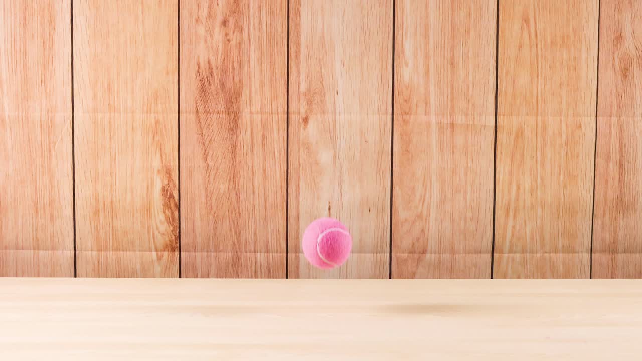 핑크색 공이 나무 바닥에서 뛰고 있다