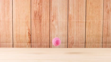 una pelota rosa rebota en un piso de madera