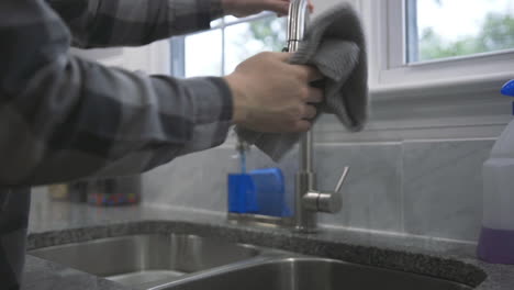 un hombre limpia el fregadero de su cocina