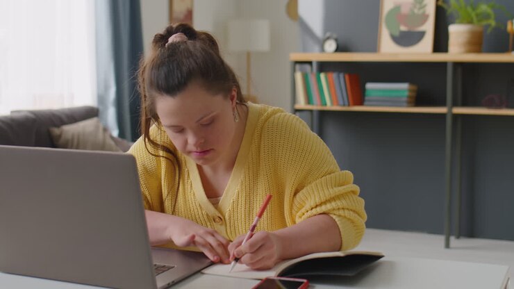 Pige med Downs syndrom bruger bærbar computer og tager noter