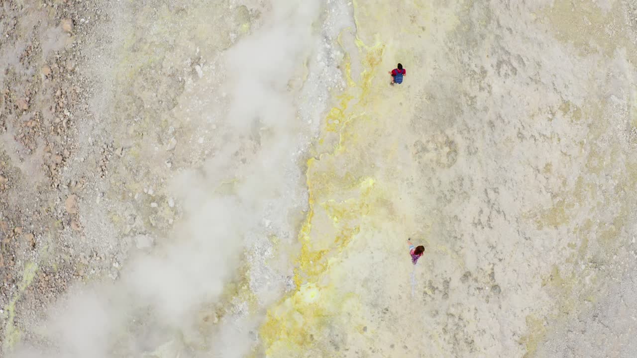 남성과 여성 산책객들이 화산에서 산책하고 황성 연기를 고 고 있습니다.