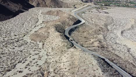 Highway-74-leading-to-small-town-with-vehicle-driving,-aerial-drone-shot