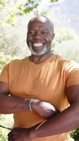 vertical video portrait of happy bald senior african american man smiling out in sun, slow motion