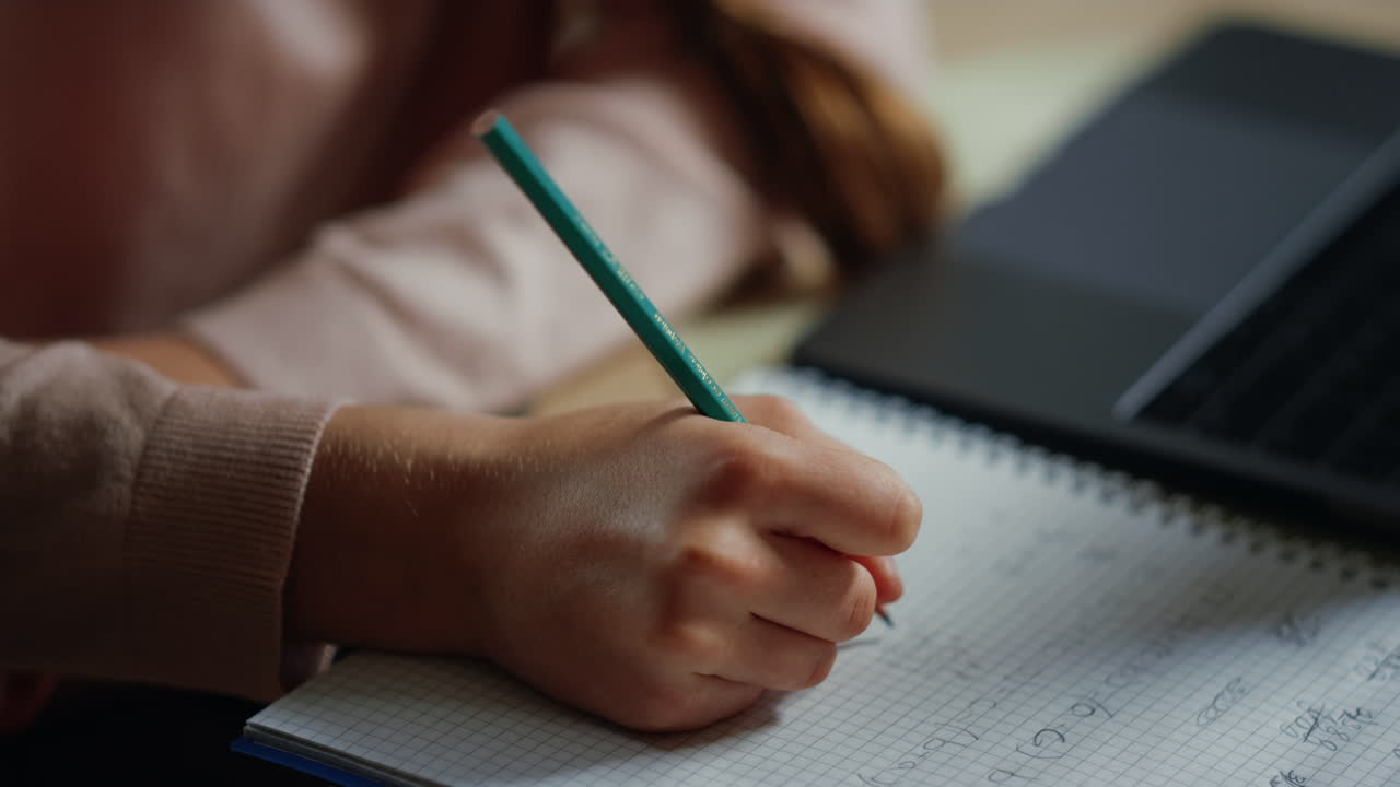Child hands solving problems in notebook. Thoughtful girl studying at home.