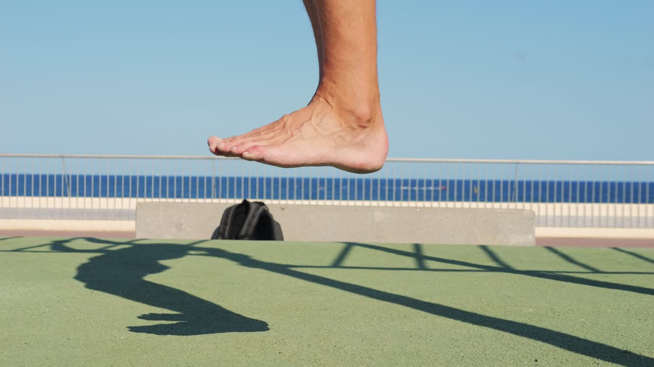 Man doing barefoot exercise on outdoor workout platform by the sea