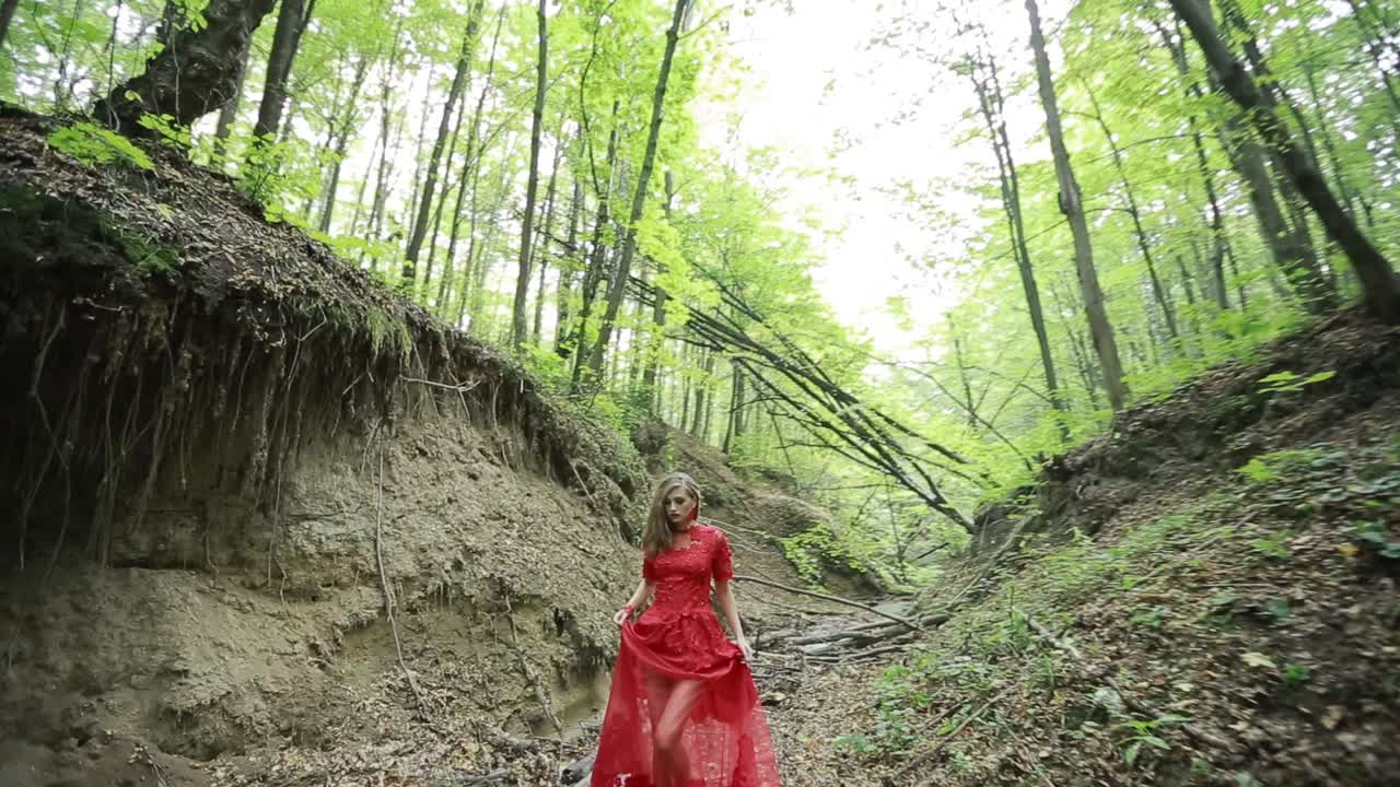 Fantasy Woman Lost In The Woods. Steadicam footage of a fantasy woman in long red dress lost in the woods
