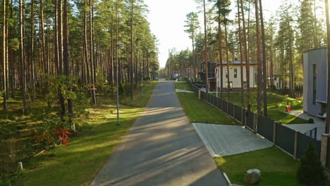 Luxury-forest-estates-with-Latvia-flag-waving-on-sunny-evening,-aerial-drone-view