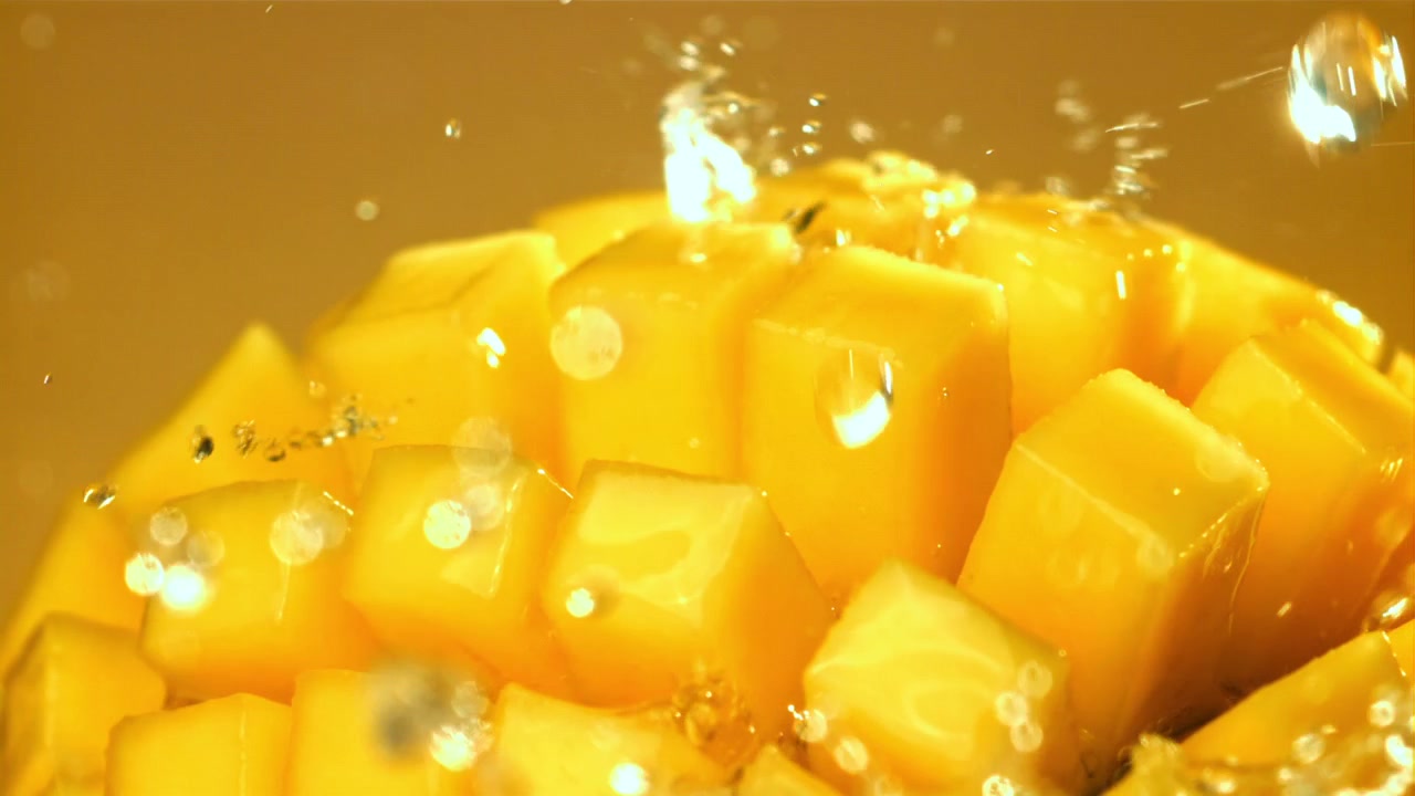 Acqua che schizza su mango fresco a cubetti al rallentatore