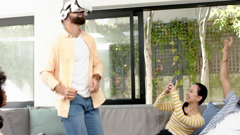 using vr headset, man playing game while diverse friends cheering on couch