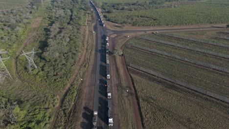 Cinematic-upward-tilt-drone-view-of-a-large-number-of-cargo-trucks-stuck-in-a-long-queue-on-a-highway-before-a-border-post