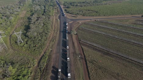 vista de avión no tripulado de inclinación cinematográfica hacia arriba de un gran número de camiones de carga atrapados en una larga cola en una autopista antes de un puesto fronterizo
