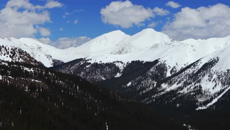 winter snow covered grays and torreys peaks sunny blue skies montezuma deer creek aerial drone colorado parallax spring rocky mountain white river national forest clouds circle left motion
