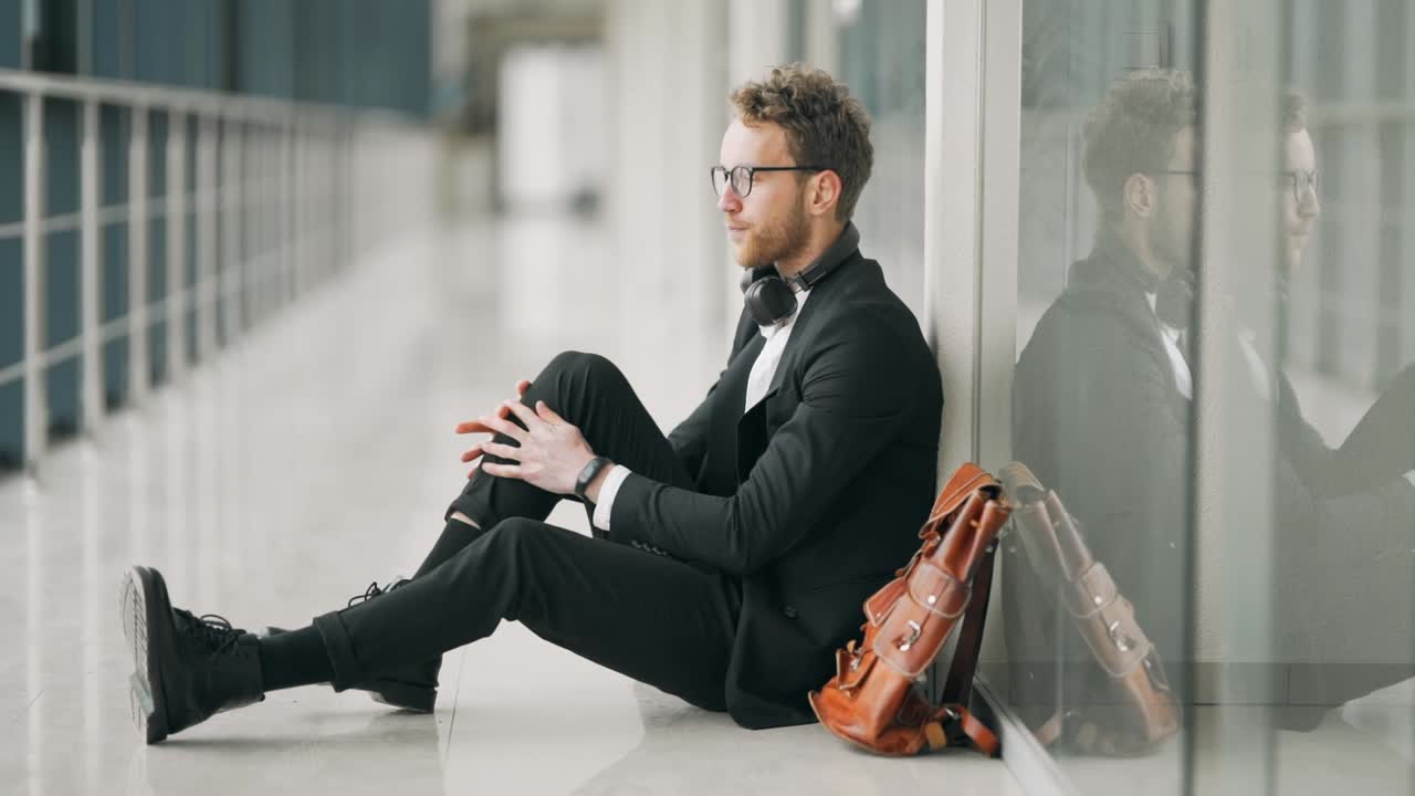 el hombre cansado sentado en el pasillo en el suelo se pone los auriculares