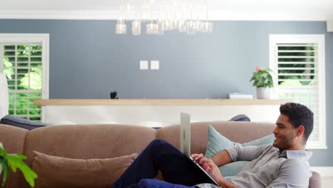 Happy-man-using-laptop-in-living-room