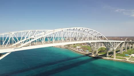 Blue-Water-Bridge-connecting-Port-Huron,-Michigan-USA-and-Sarnia,-Ontario-Canada-with-drone-moving-up