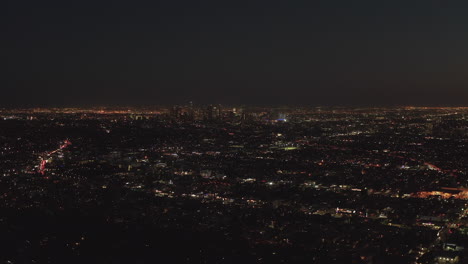 Aéreo:-Vuelo-Lento-Sobre-Las-Colinas-De-Hollywood-Por-La-Noche-Con-Vistas-Al-Horizonte-Del-Centro-De-Los-ángeles