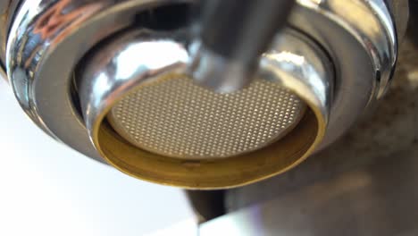 professional barista locking the portafilter on to the group head coffee machine