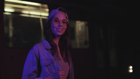 teenager caucasian girl with glasses and cap smiling and posing for the camera outdoors at night