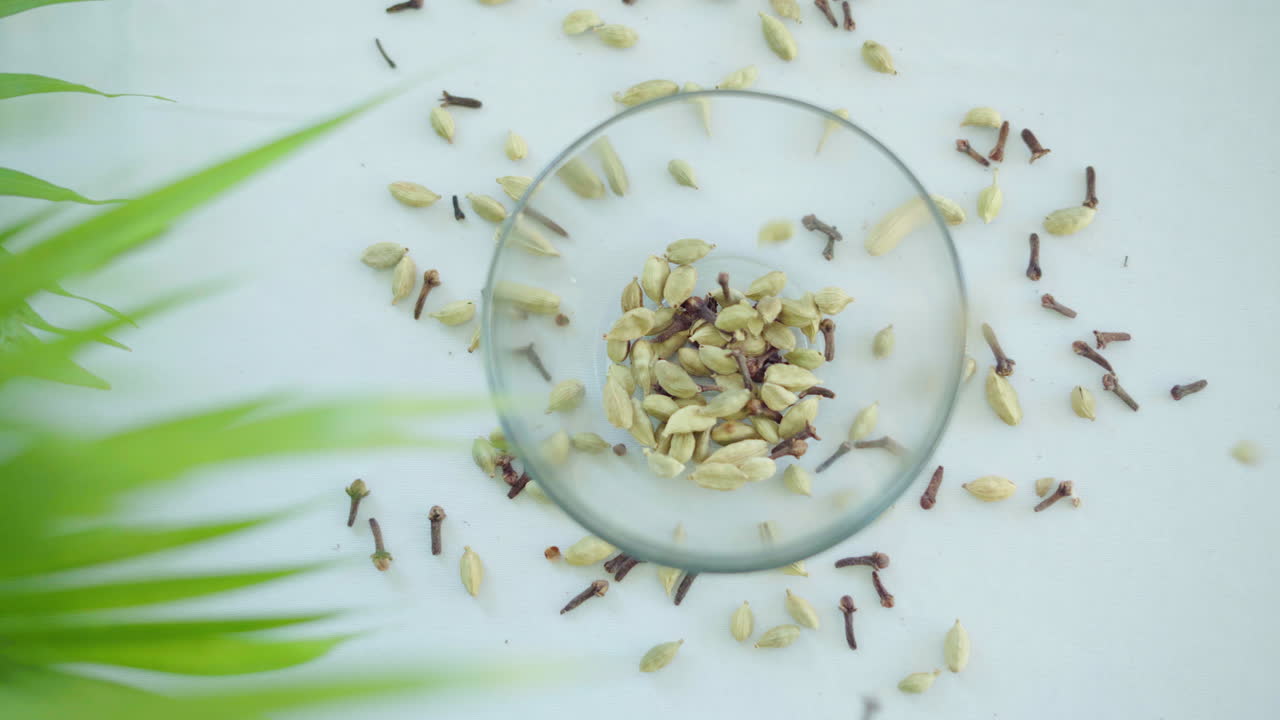 흰색 배경에 있는 유리 그릇에서 빠른 동작으로 떨어지는 향신료 믹스 위에 패닝 탑 샷