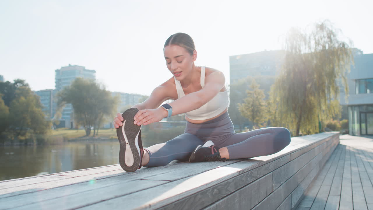 백인 젊은 여성이 피트니스, 건강 및 웰빙을 위해 도심 공원에서 다리를 펴고 있습니다.