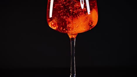 a series of images showing an orange liquid with bubbles in a glass against a dark background.